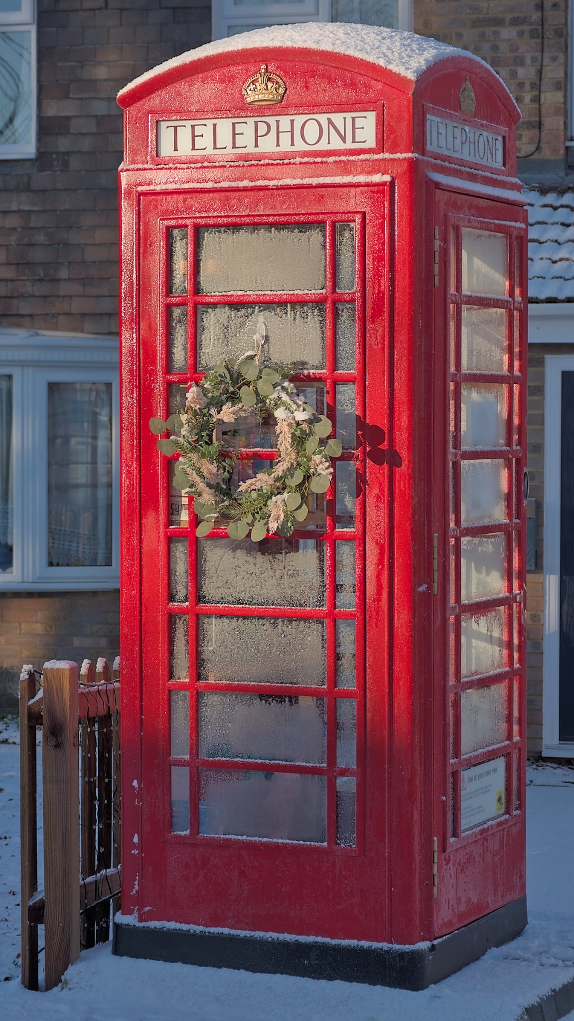 Red K6 phonebox book exchange on a frosty morning with snow